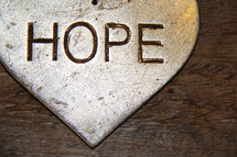 The word hope on a silver ornament with wooden background