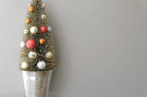 small decorated Christmas tree against a white/grey background 