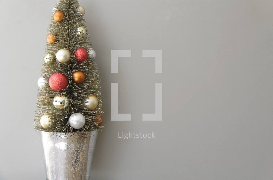 small decorated Christmas tree against a white/grey background 