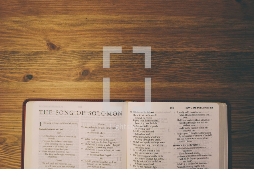 Bible on a wooden table open to the book of the Song of Solomon.