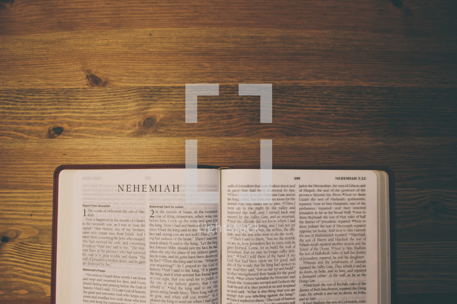 Bible on a wooden table open to the book of Nehemiah.