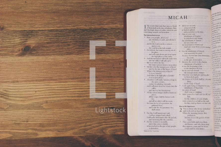 Bible on a wooden table open to the book of Micah.