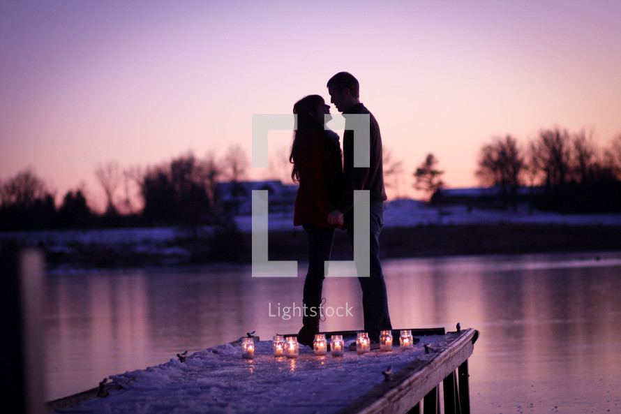 silhouette of a couple on a dock and candles 