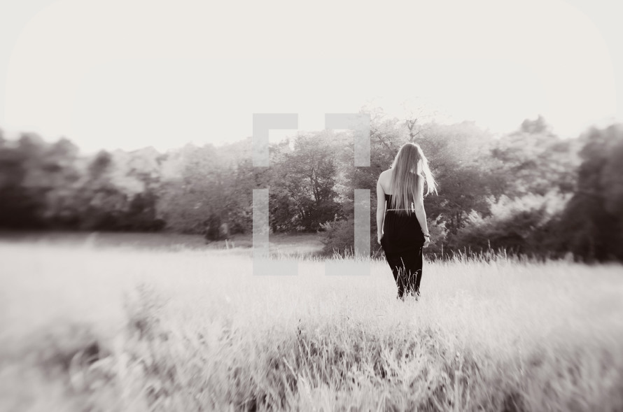 woman in a black dress walking in a field
