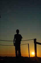 silhouette of a young boy standing outdoors 