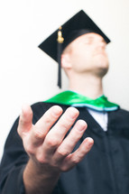 Graduate with hands extended n prayer.