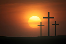 three crosses against a red/orange sky a sunset 