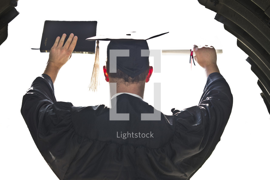 graduate holding up his diploma and a Bible