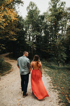 couple walking holding hands on a dirt road 