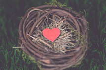 A wooden heart in a bird's nest