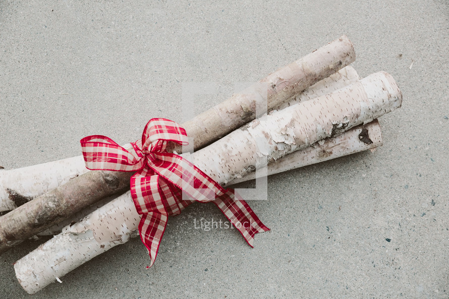 Birch logs tied together with red and white ribbon.