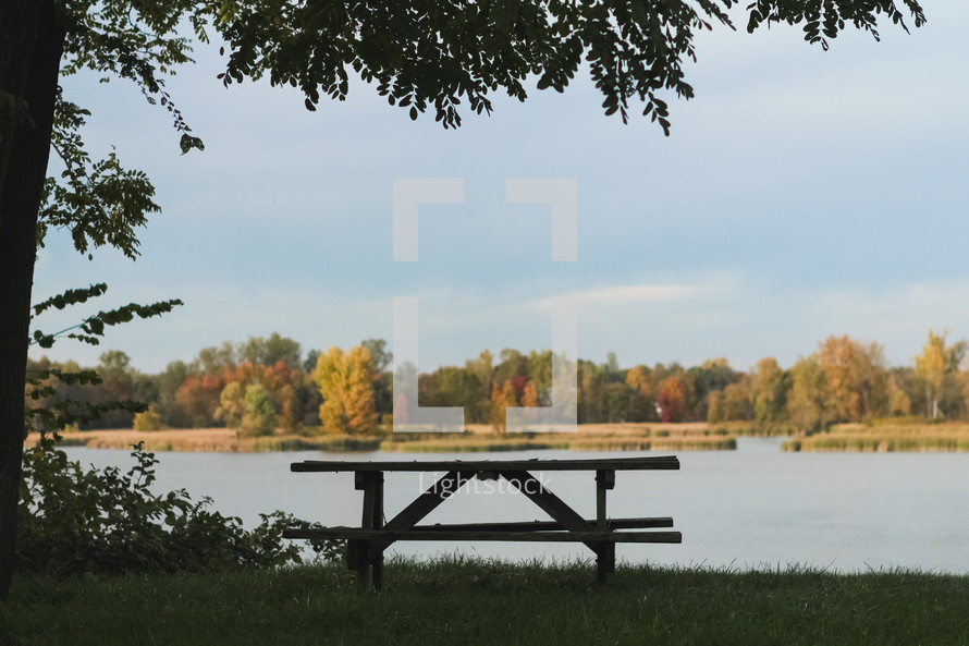 picnic bench by a lake in a park in fall 