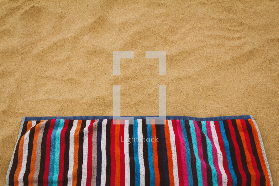 striped beach towel on sand background 