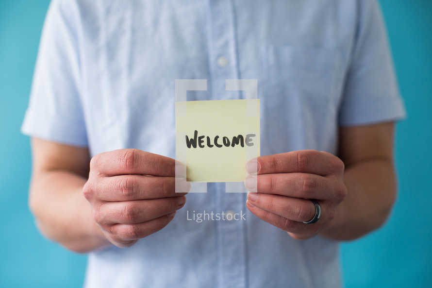 man holding a piece of paper with word welcome