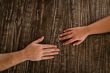 couple's hands on a wooden table 
