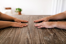 a couple's hands on a wooden table 