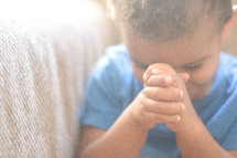 a toddler with praying hands 