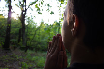 boy praying in a forest 