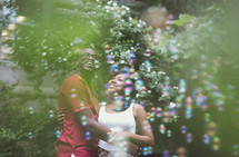 An African American couple in love looking up at bubbles 