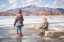 children playing outdoors in puddles from melting snow 