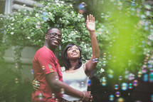An African American couple in love reaching for bubbles 
