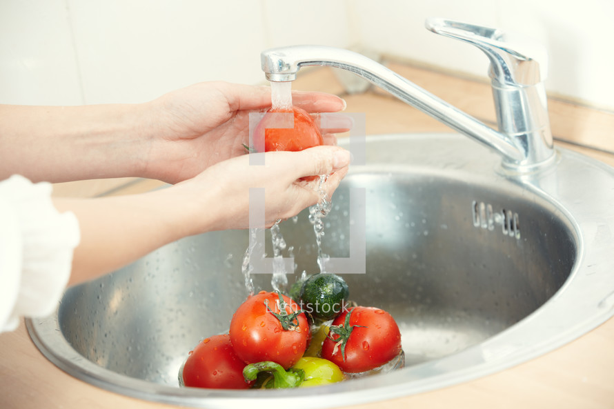 woman washing vegetables in a sink 