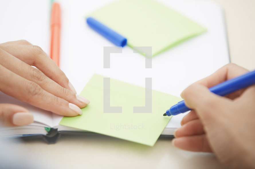 woman writing on a blank sticky note