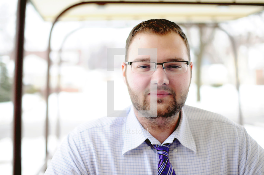face of a man wearing a tie and dress shirt and glasses 