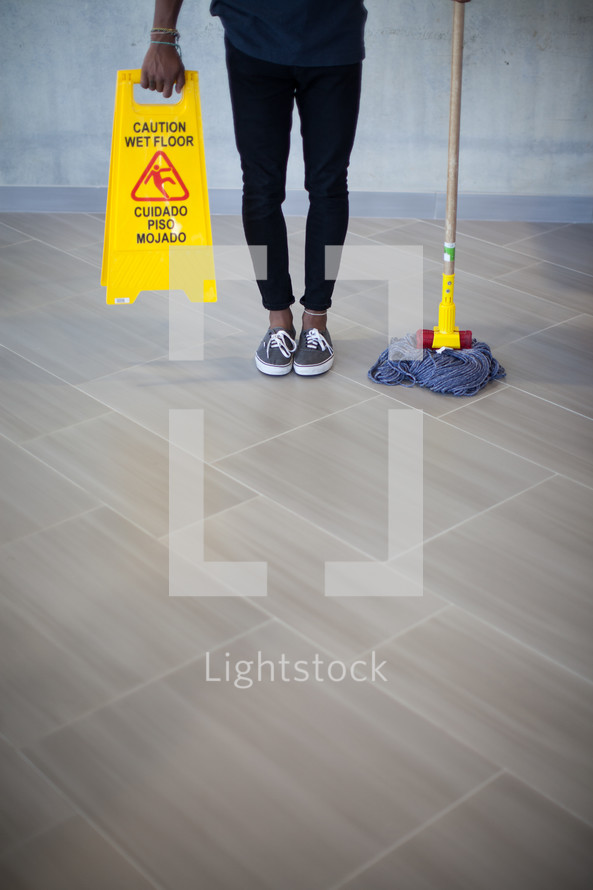 a man holding a mop and wet floor sign 