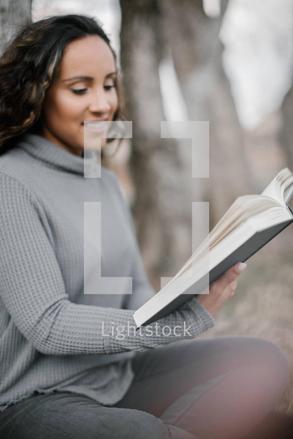 a young woman reading a Book outdoors 
