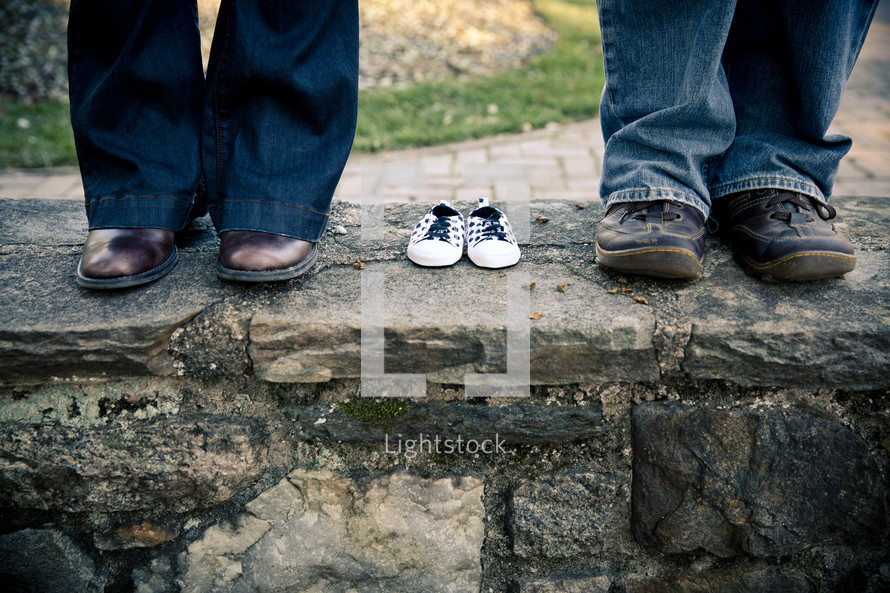 shoes on a man and woman standing next to empty baby shoes