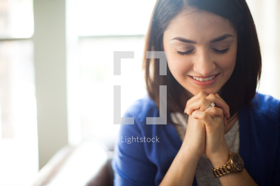 A young woman with hands clasped in prayer.