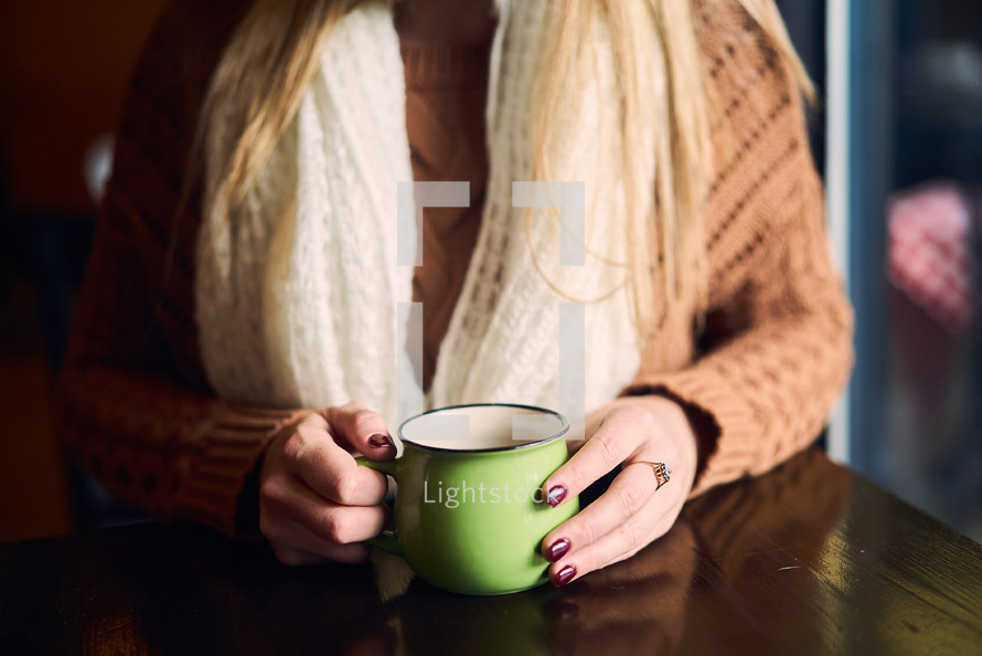 a woman in a sweater holding a coffee cup 