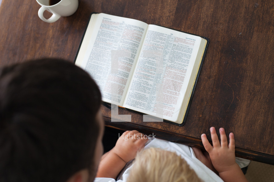 morning devotional - man and his toddler son reading a Bible and a cup of coffee 