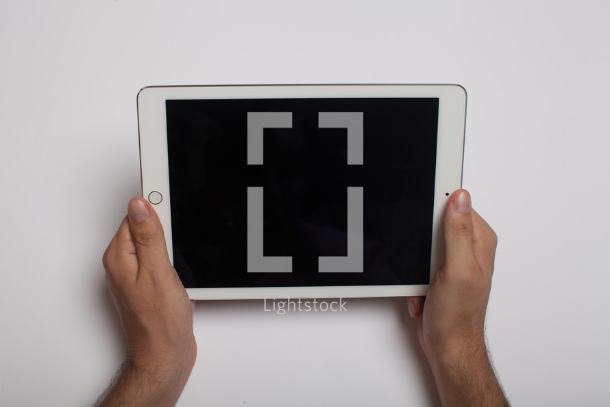 Hands holding an electronic tablet on a white background.
