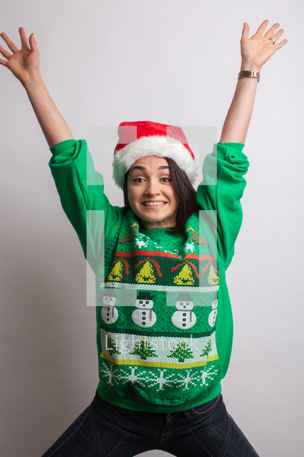 woman in an ugly Christmas sweater and santa hat celebrating 
