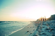 Guys standing on the seashore at sunset