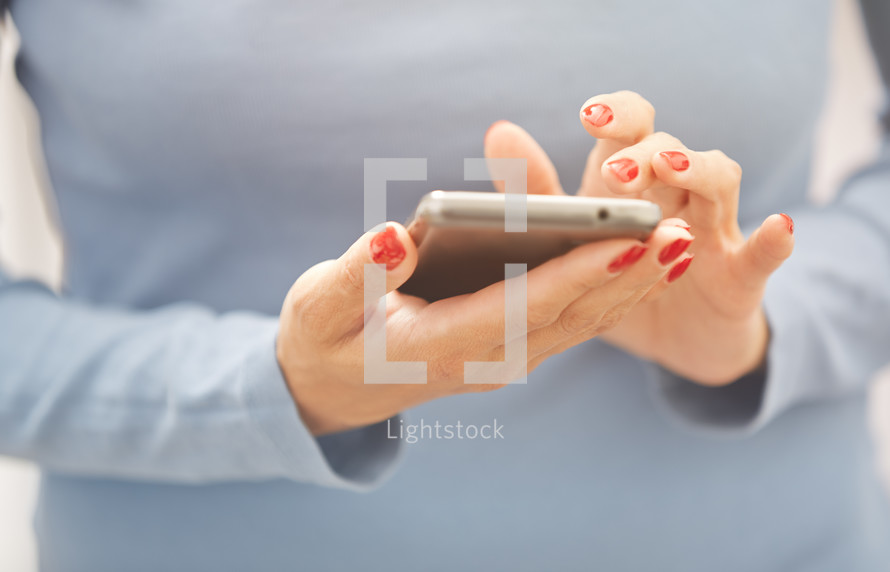 a woman with painted nails using a cellphone 