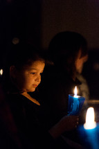 a child holding a candle at a Christmas Eve Candlelight service 