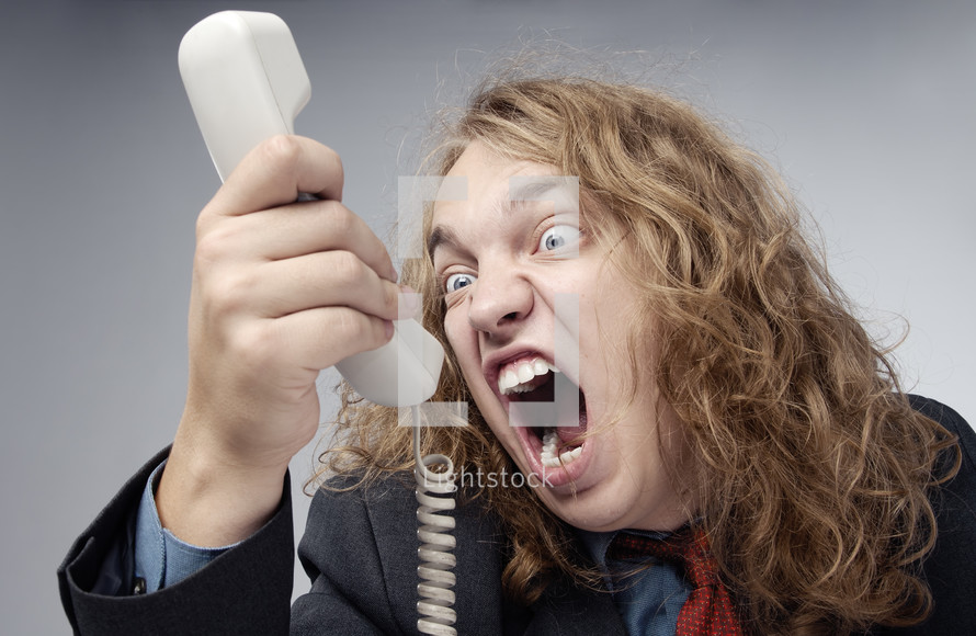 A man screaming at a telephone 