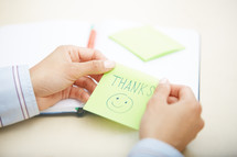 woman holding a sticky note with the word thanks 