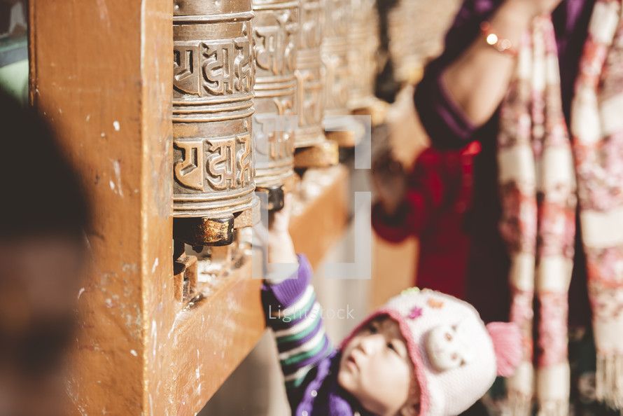 toddler at a prayer wheel in Nepal 