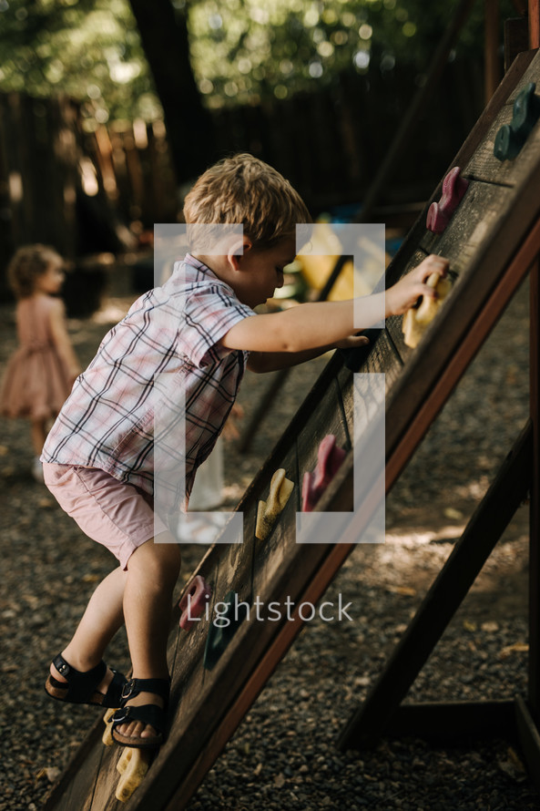 children climbing a climbing wall on a playground 