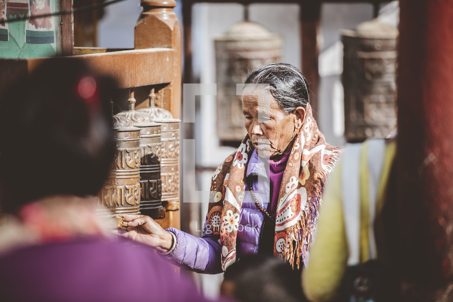 women praying at a prayer wheel in Nepal
