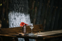 wine glass and mason jar of flowers on a picnic table 