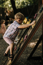 children climbing a climbing wall on a playground 