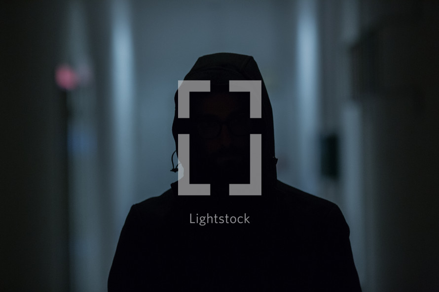 dark silhouette of a man in a hoodie 