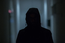 dark silhouette of a man in a hoodie 