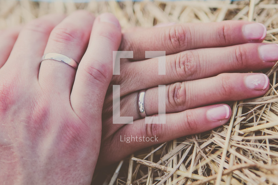 a couple holding hands with wedding bands 