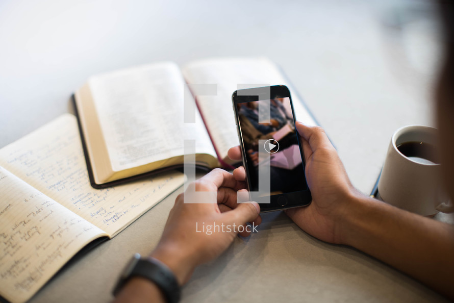 overhead view, coffee mug, smartphone, opened Bible, and notebook on a table